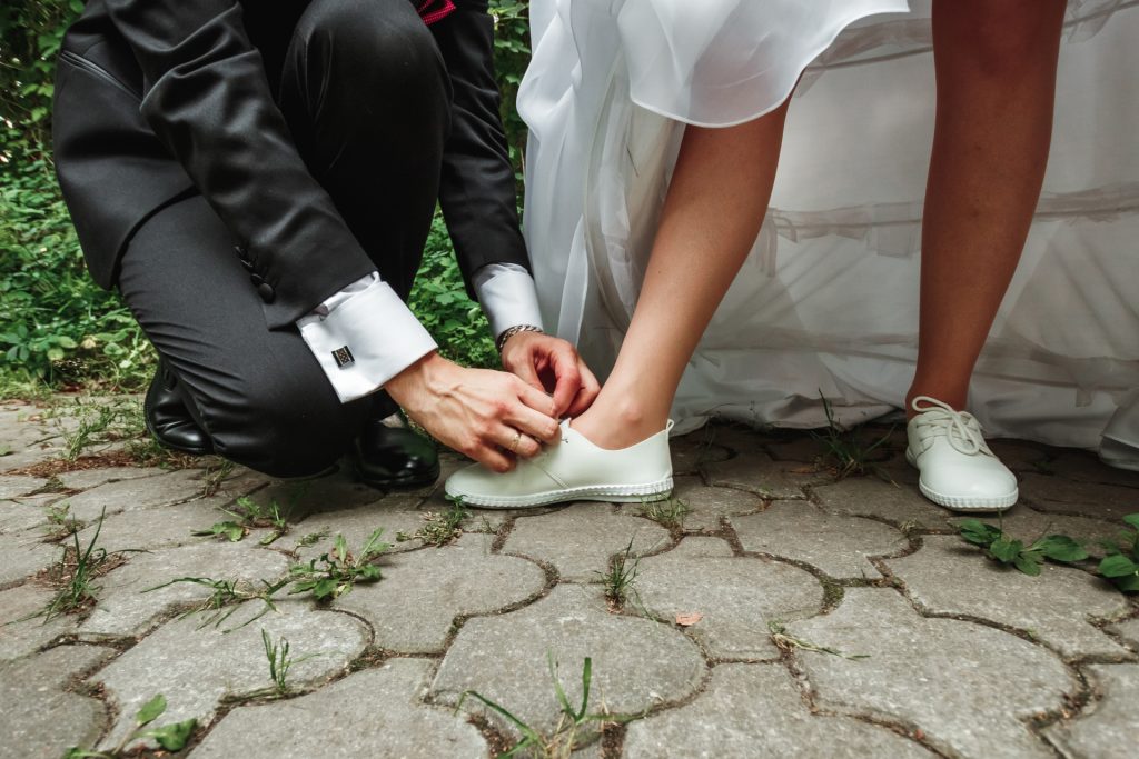 Submissive man ties up the bride's shoes